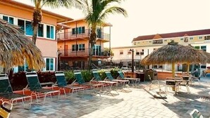 A pool area with lounge chairs and umbrellas, surrounded by buildings with balconies. - Coral Shores Resort (North Redington Beach)