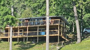A multi-story wooden cabin with balconies, surrounded by trees.