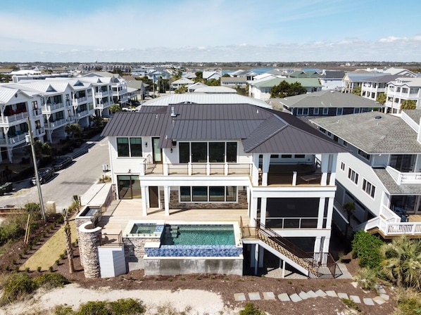 Uma casa moderna de vários andares com uma varanda espaçosa, piscina e vista para o oceano.