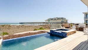Zona de piscina con hidromasaje, mobiliario exterior y vistas a la playa y al océano.