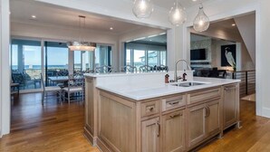 Una cocina amplia con una isla grande, armarios de madera e iluminación colgante.