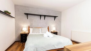 A neatly arranged bedroom with a bed, bedside tables, and a shelf with plants. - 5 Guests - 2-bed House - Bbq - Free Parking (Norwich)