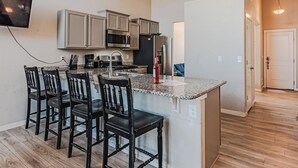 A kitchen with a granite countertop, stainless steel appliances, and a TV mounted on the wall. - •Wacissa Lookout View - Wine, GameRoom, HotTub• (Colorado Springs)