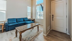 A living room with a blue sofa, a wooden coffee table, and a chandelier. - •Wacissa Lookout View - Wine, GameRoom, HotTub• (Colorado Springs)