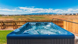 A hot tub with a wooden fence and a view of houses and mountains in the background. - •Wacissa Lookout View - Wine, GameRoom, HotTub• (Colorado Springs)