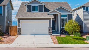 A two-story house with a garage, a small front porch, and a well-maintained lawn. - •Wacissa Lookout View - Wine, GameRoom, HotTub• (Colorado Springs)