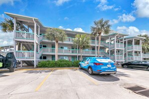 A multi-story hotel with balconies, a parking lot, and palm trees. - 🌟 50Ft from Beach Access- Pool View- Budget Friendly- 1BR Nautical Watch E-3🌟 (Panama City Beach)