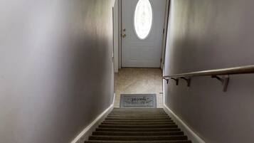 A carpeted staircase leading to a door with a circular window.