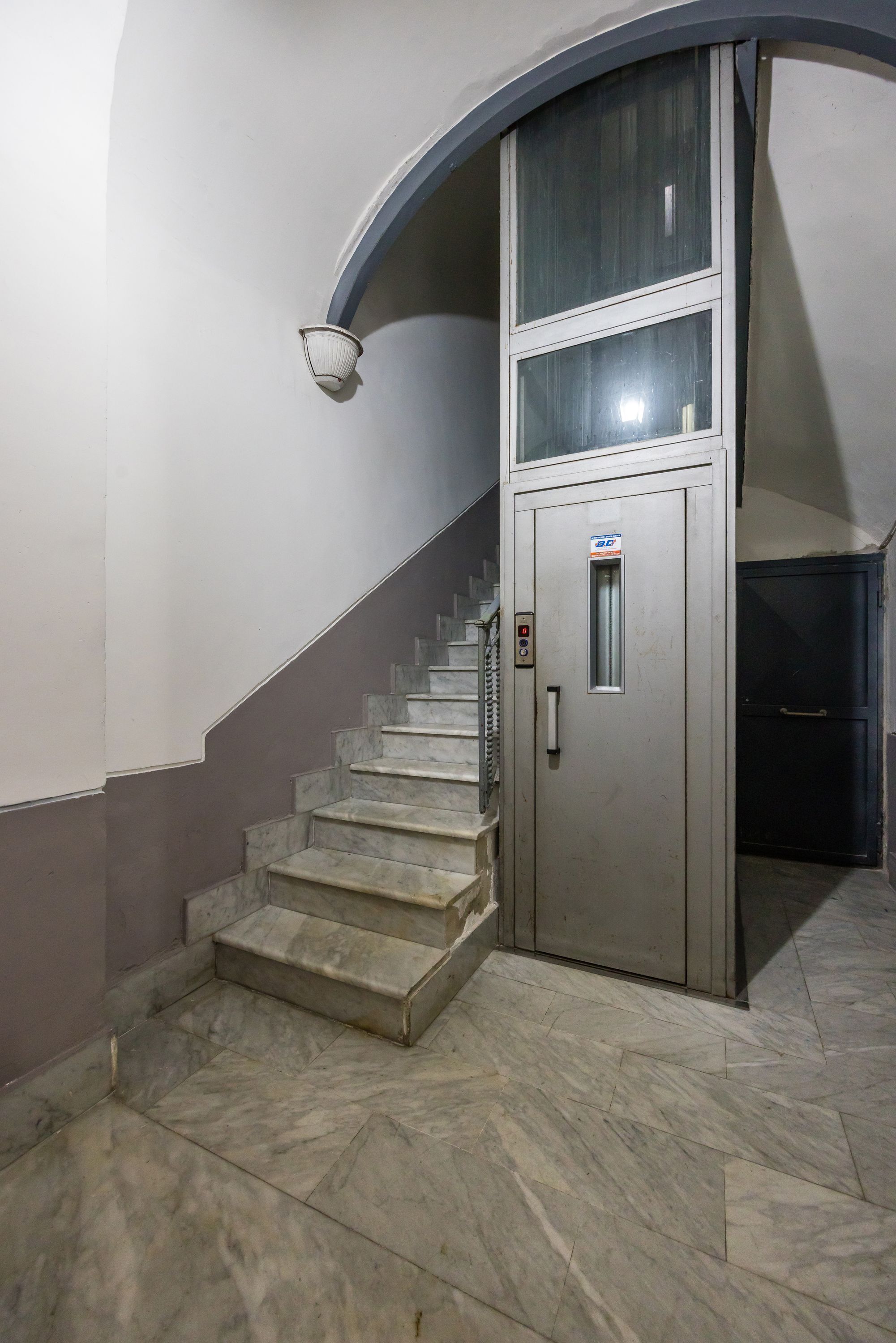 A staircase with a metal handrail leading to a door with a security keypad.