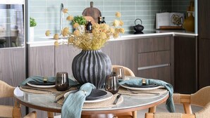 A dining table set with plates, glasses, and a vase of dried flowers. - Designer Penthouse Panoramic Views London 2 Beds (London)