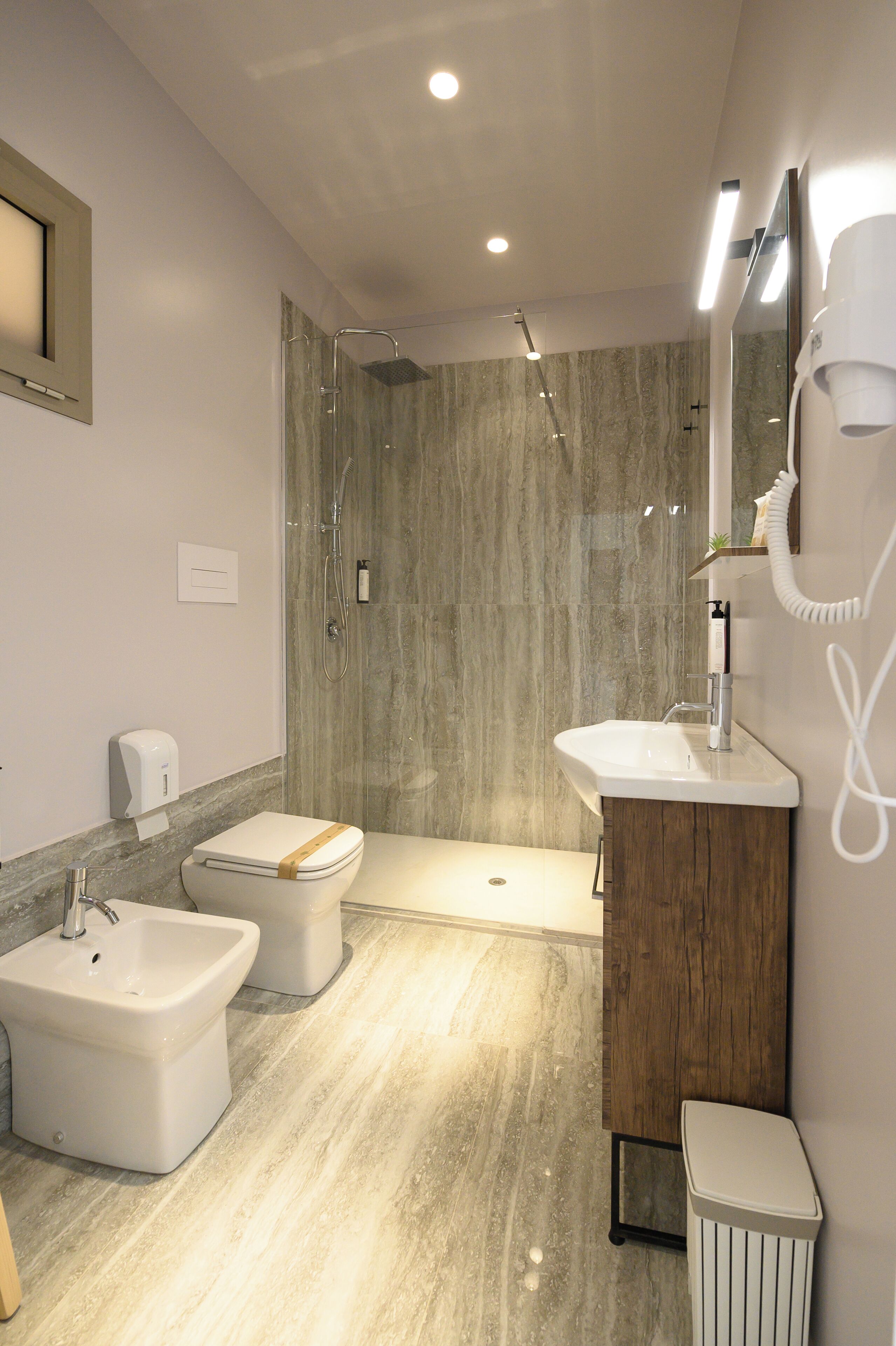 A modern bathroom with a shower, bidet, sink, and toilet.