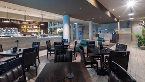 A modern hotel lobby with a bar area, seating arrangements, and a staircase leading to an upper level. - Baitan Hotel (Marsala)