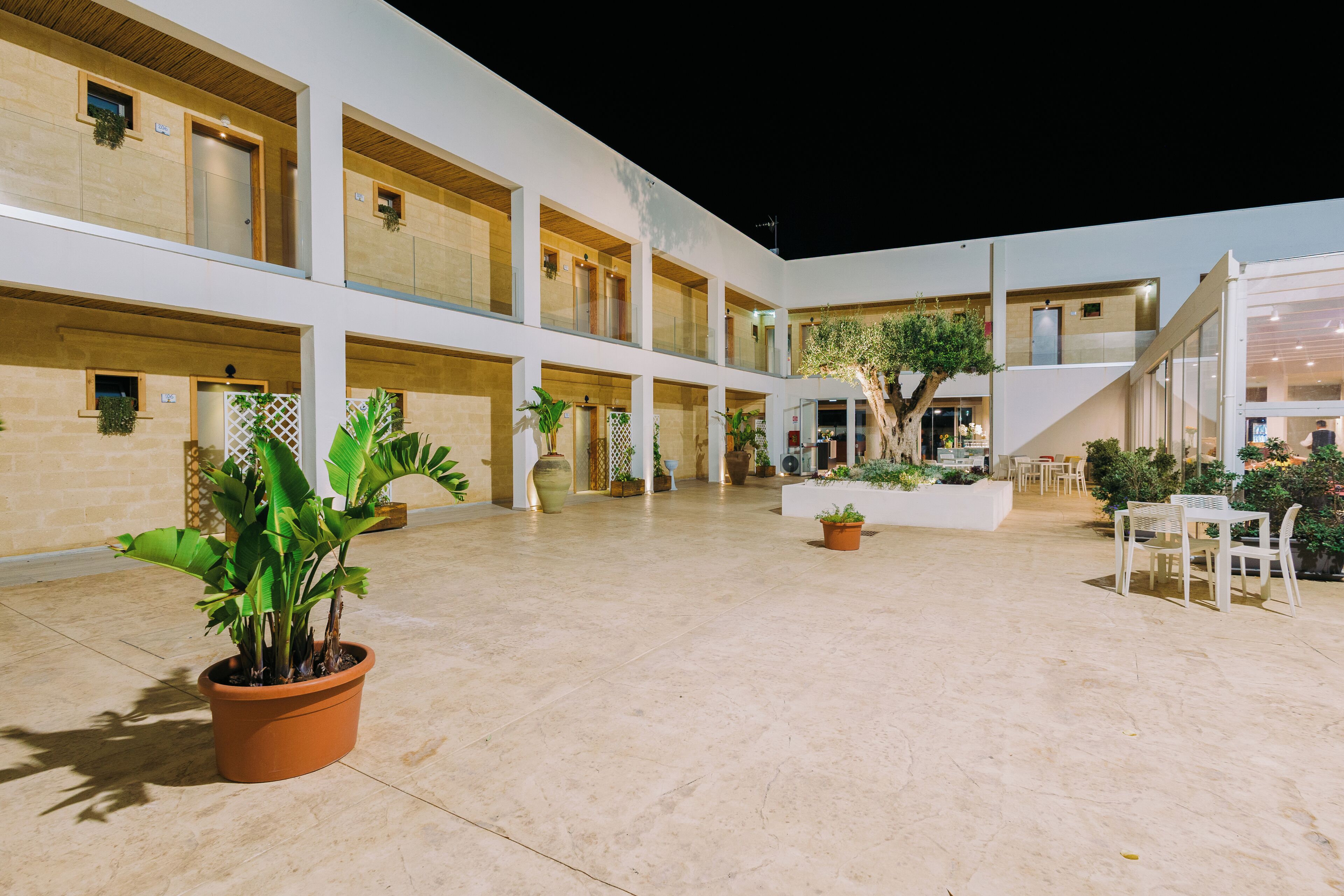 A spacious indoor courtyard with multiple levels, potted plants, and seating areas.