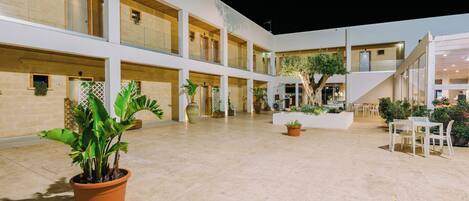 A spacious indoor courtyard with multiple levels, potted plants, and seating areas.