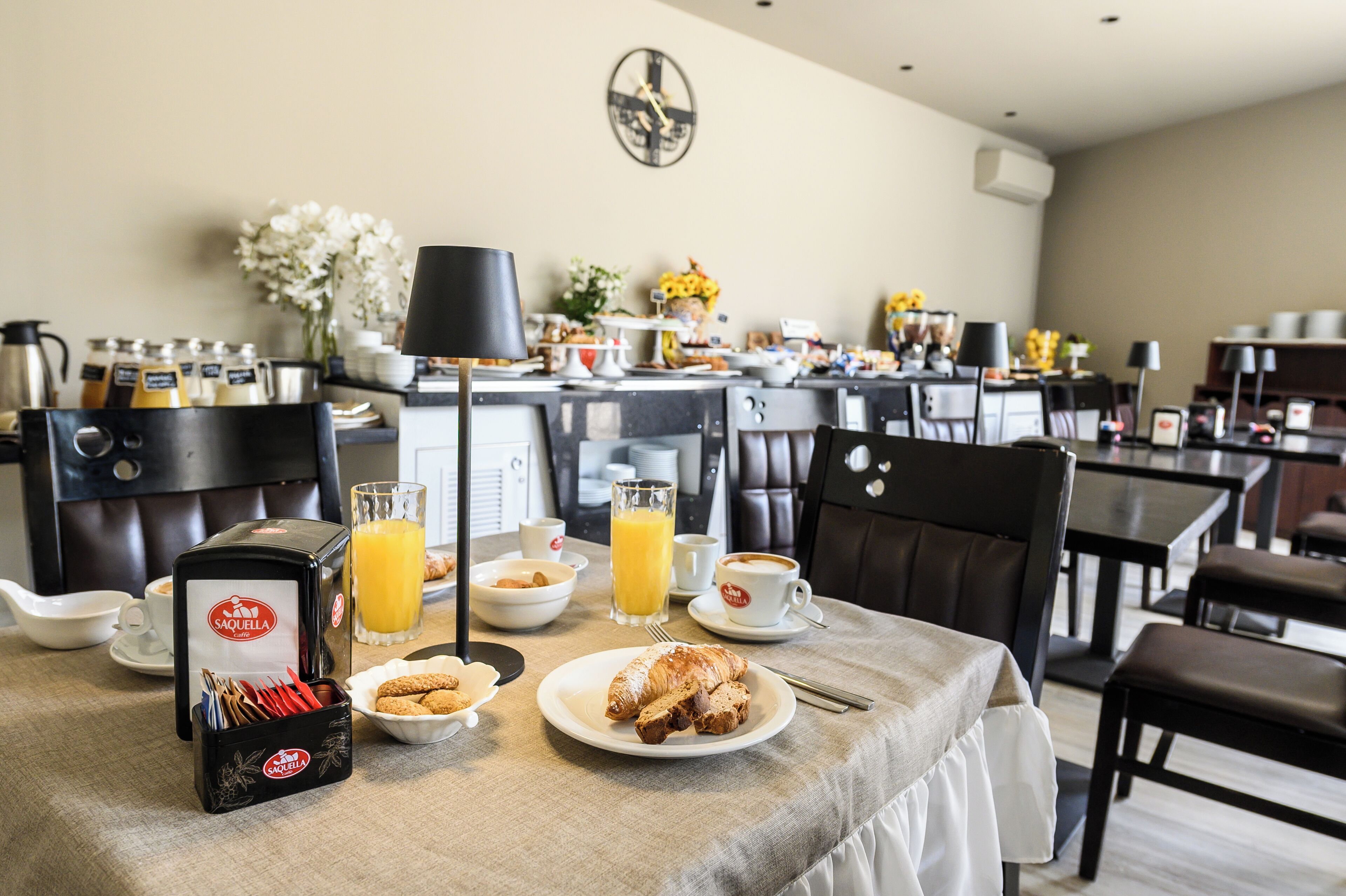 A breakfast setup with croissants, orange juice, and coffee on a table in a hotel dining area.