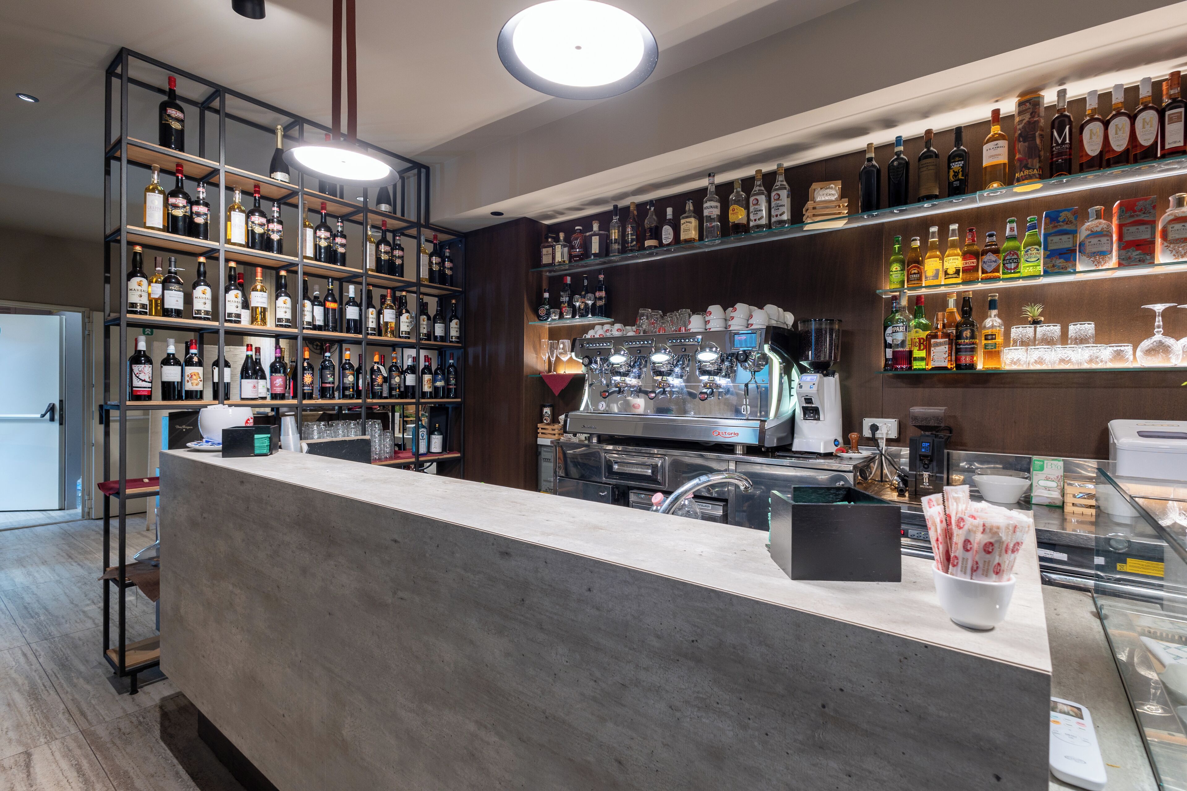 Eine Bar mit Regalen voller Spirituosenflaschen, einer Kaffeemaschine und einer Kasse.