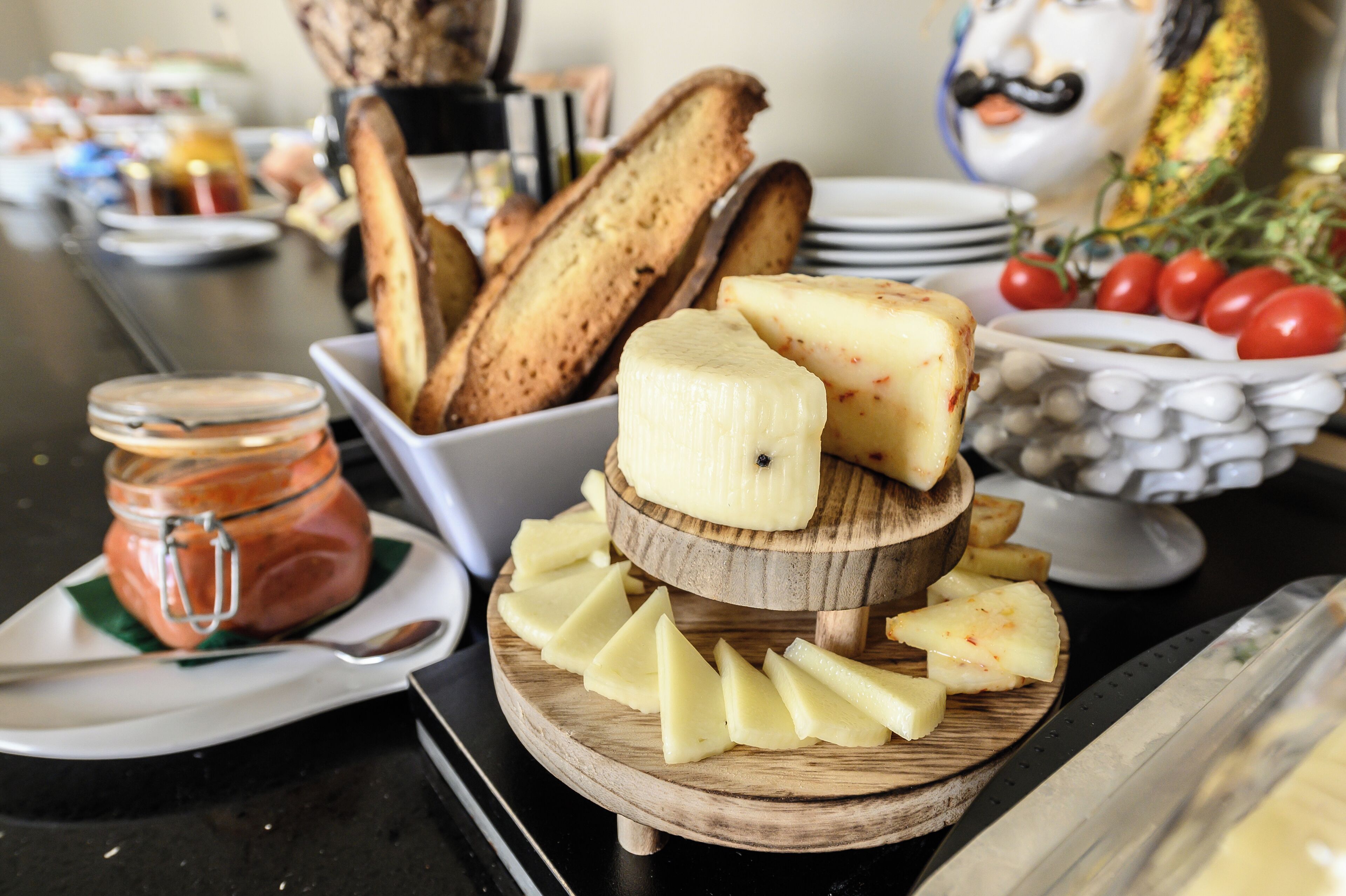 Een buffet met verschillende gerechten, waaronder kaas, brood en tomaten.