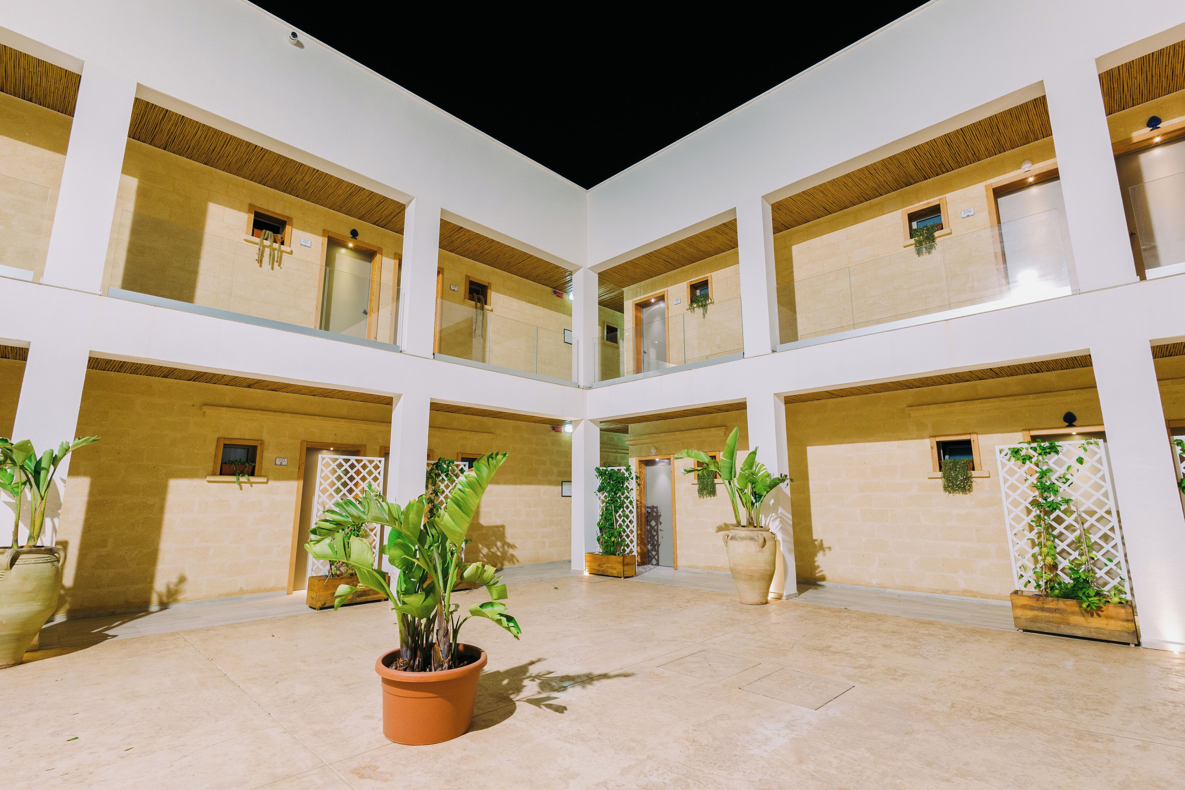 A spacious atrium with multiple balconies, potted plants, and a central open area.