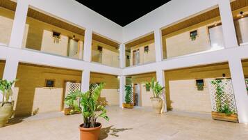 A spacious atrium with multiple balconies, potted plants, and a central open area.