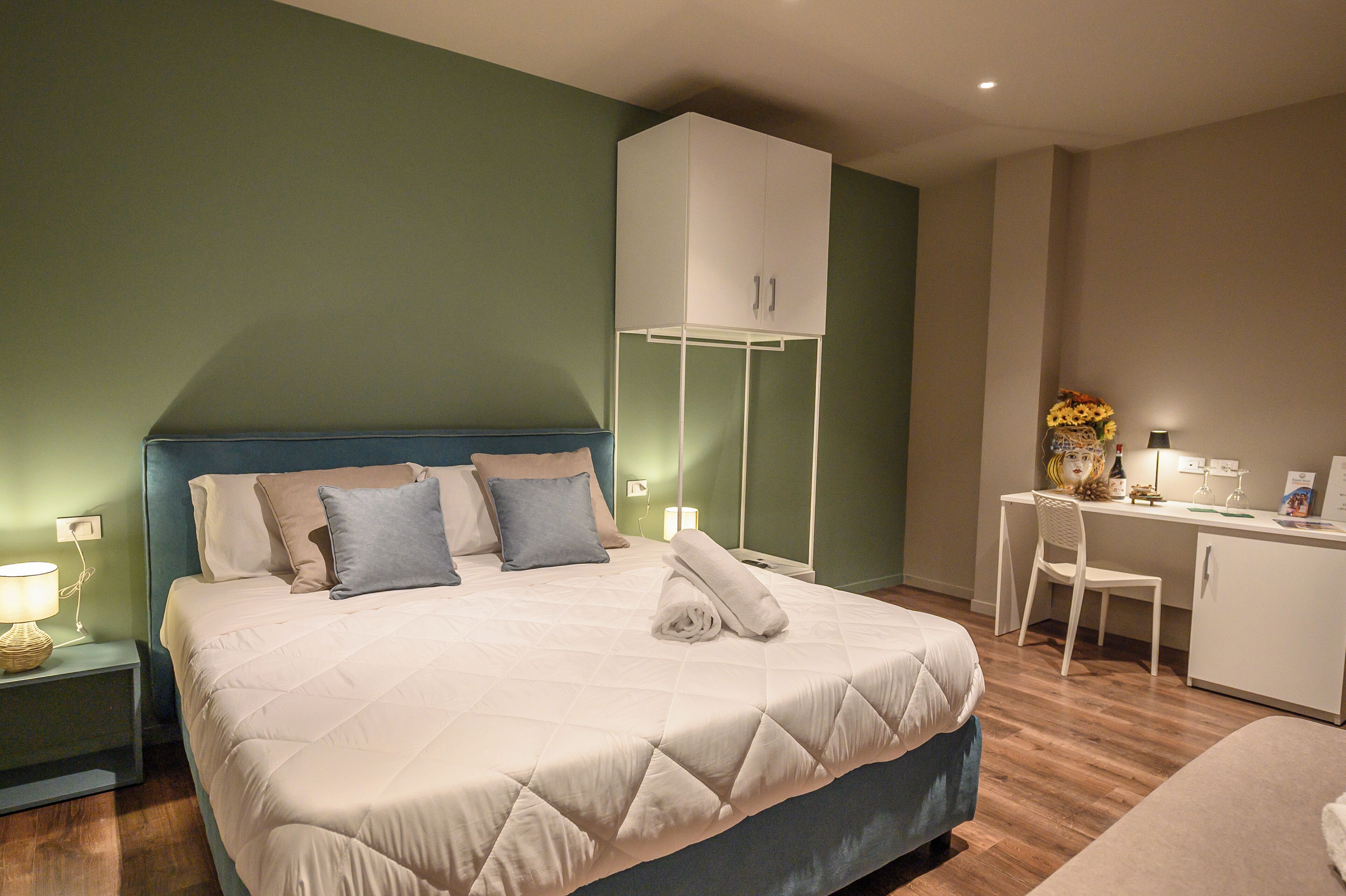 Un dormitorio ordenado con cama, mesita de noche, escritorio y silla.