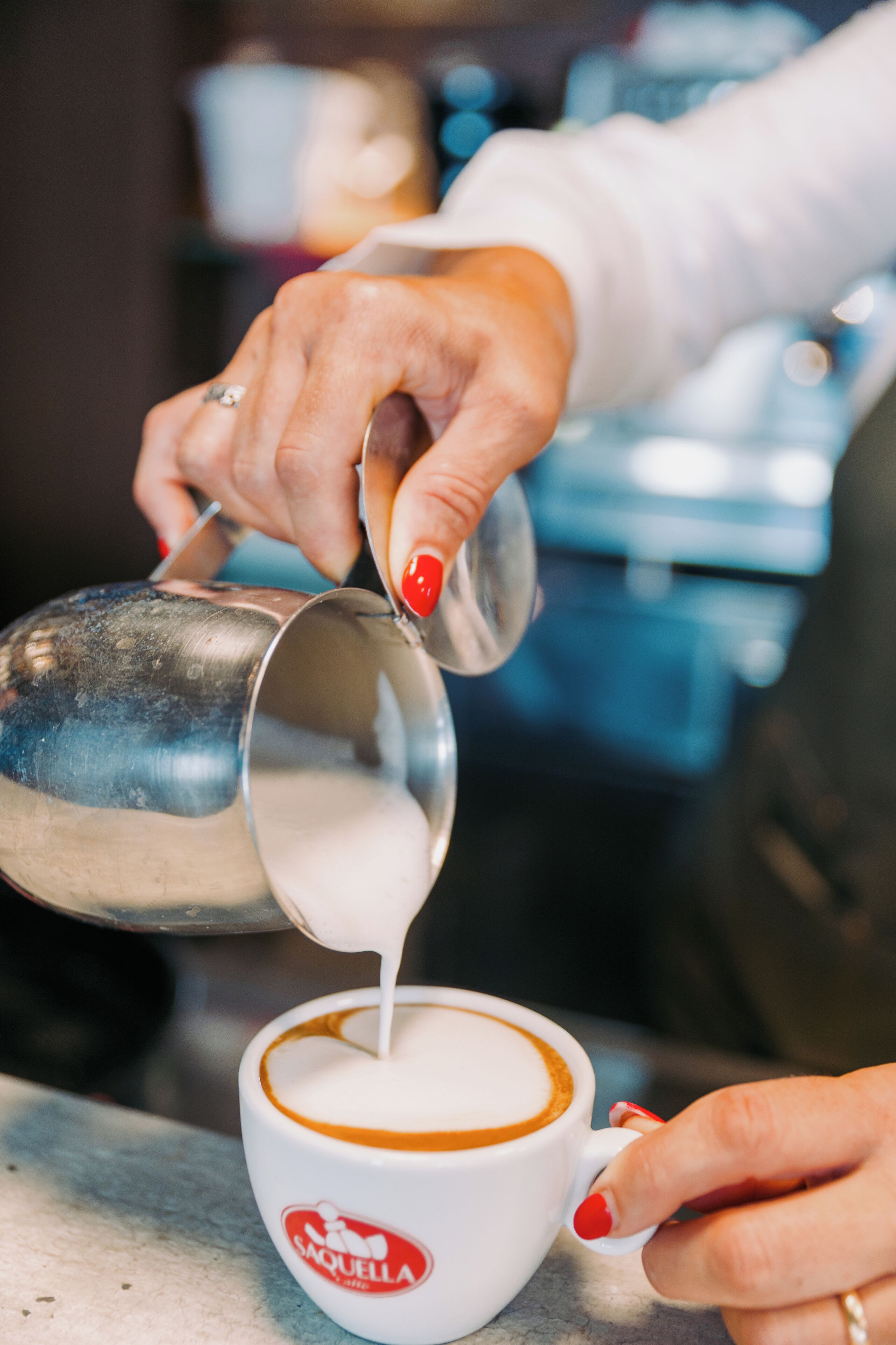A person pouring milk into a cup of coffee.