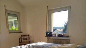 A bedroom with a bed, a chair, a window, and a radiator. - Erholen, Entspannen, Genießen und Entdecken Eine Oase der Ruhe im Westerwald (Goddert)