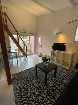 Relax in this stylish living area with a flat-screen TV and comfortable seating, leading to an outdoor space with a glass door.