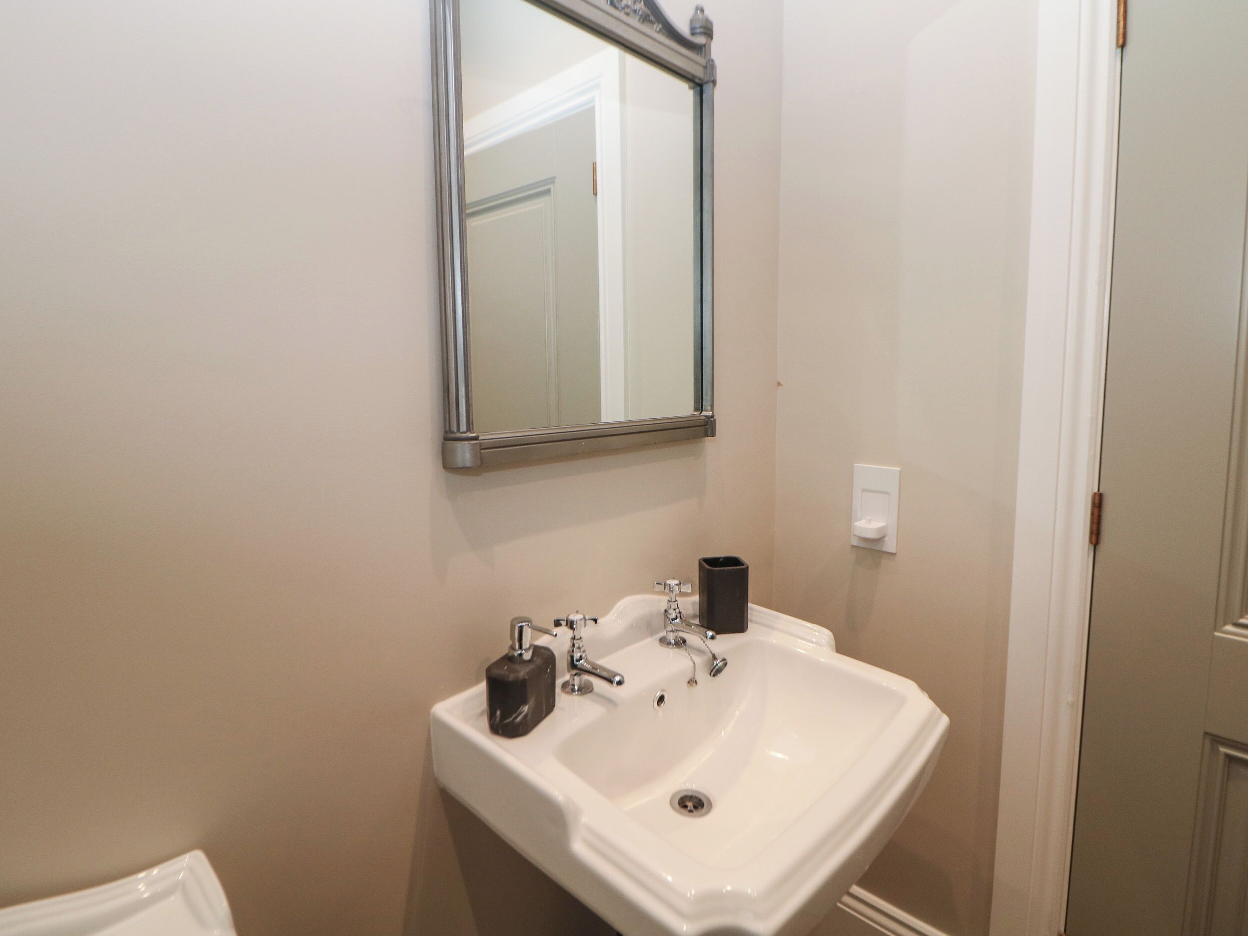 A bathroom with a white sink, a mirror, and a door.