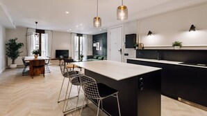 A modern kitchen with a central island, black cabinetry, and pendant lighting. - Lunalux - Habitat Apartments (Barcelona)