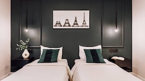 A modern hotel room with two beds, a dark wall, and a framed picture of the Eiffel Tower. - Lunalux - Habitat Apartments (Barcelona)