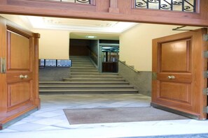 A wooden double door entrance with a carpet leading to a staircase.