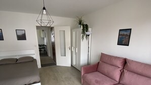 Une chambre à coucher moderne avec un lit, un canapé rose et une armoire blanche.