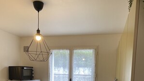 Une cuisine compacte avec un réfrigérateur blanc, un four à micro-ondes, une table à manger avec quatre chaises et un luminaire suspendu.