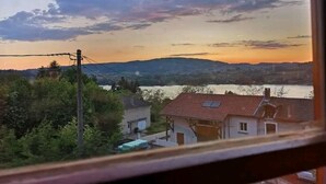 A view of a residential area with houses and a body of water during sunset. - La Ferme Tchoukar, Ferme Dauphinoise à 10min du lac à Pied (BILIEU)