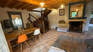 A cozy room with a wooden dining table, a staircase, a fireplace, and a large mirror on the wall. - La Ferme Tchoukar, Ferme Dauphinoise à 10min du lac à Pied (BILIEU)
