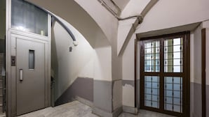 A hallway with a marble floor, a door with a glass panel, and a staircase.