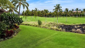 A well-maintained golf course with lush green grass, palm trees, and a clear blue sky. - Colony Villas Waikoloa 301 (Waikoloa)