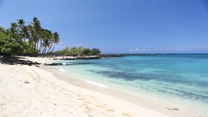 A beach with clear turquoise water, white sand, and palm trees. - Colony Villas Waikoloa 301 (Waikoloa)
