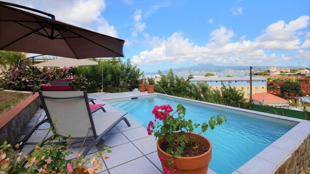 A swimming pool with a view of a cityscape, a chair, and a potted plant. - Villa Cécia - Four Bedroom Villa, Sleeps 8 (Les Trois-Îlets)
