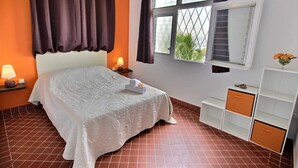 A neatly arranged bedroom with a bed, two bedside lamps, a window with curtains, a small table with a lamp, and a white cabinet with drawers. - Villa Cécia - Four Bedroom Villa, Sleeps 8 (Les Trois-Îlets)