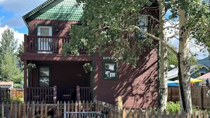 A two-story building with a balcony, a wooden fence, and a sign that reads 'Seven Oaks.'