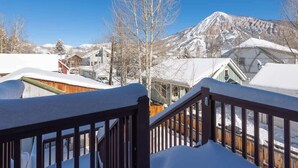 A snowy mountain landscape with a clear sky, a wooden staircase leading to a building, and snow-covered rooftops.