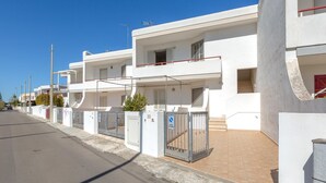 A row of modern white buildings with balconies, a gated entrance, and a clear blue sky. - 3796 Casa Solero by Barbarhouse (Melendugno)