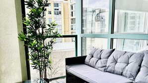 Ein Balkon mit Glastisch, Rattan-Sofa und einem Blumentopf.