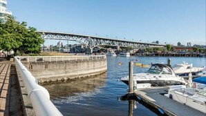 Ein Yachthafen mit vertäuten Booten, im Hintergrund eine Brücke und eine Uferpromenade.
