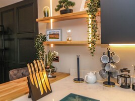 A kitchen with wooden shelves, a coffee maker, and various utensils.