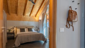 Un dormitorio con cama, mesitas de noche, lámpara, ventana y bolso colgado en la pared.