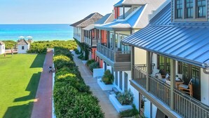 A coastal hotel with multiple-story buildings, a paved walkway, and a view of the ocean.
