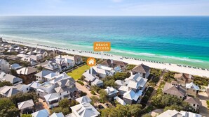 A coastal residential area with beach access, featuring houses with varied roof styles and a clear view of the ocean.