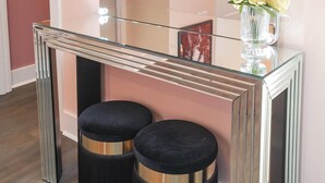 A vanity with a mirror, lights, and two stools.